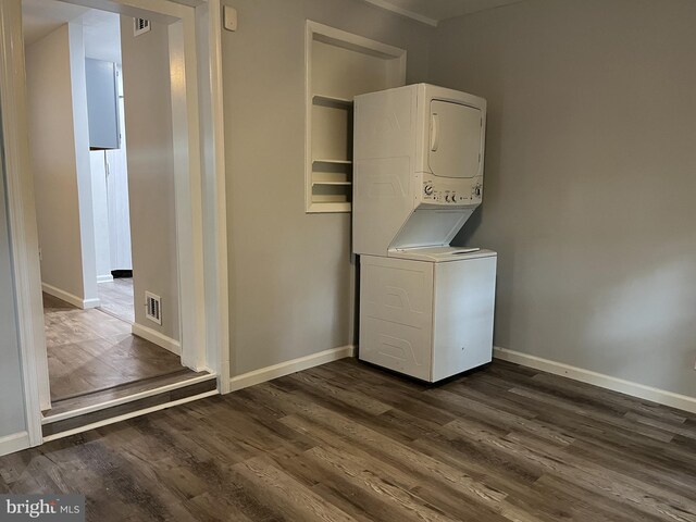 clothes washing area featuring dark hardwood / wood-style floors and stacked washer / drying machine