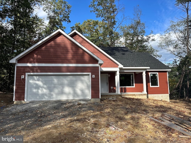 view of front of house featuring covered porch, driveway, a shingled roof, and a garage