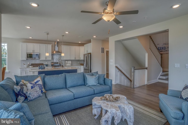 living room with recessed lighting, wood finished floors, visible vents, ceiling fan, and stairs