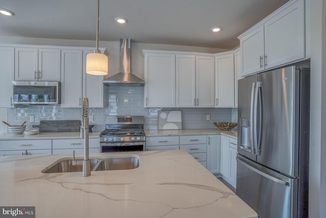 kitchen with decorative light fixtures, backsplash, stainless steel appliances, and wall chimney exhaust hood