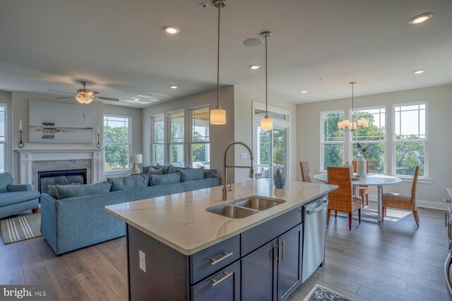 kitchen with a sink, open floor plan, decorative light fixtures, and a kitchen island with sink