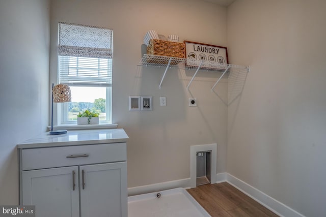 clothes washing area featuring baseboards, cabinet space, wood finished floors, washer hookup, and hookup for an electric dryer