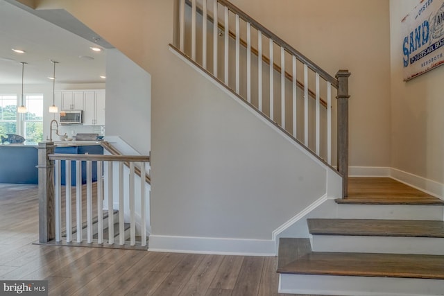 stairway featuring sink and light hardwood / wood-style floors