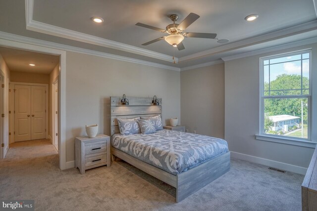 carpeted bedroom with ceiling fan, a tray ceiling, and ornamental molding