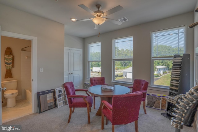 dining area featuring visible vents, light colored carpet, a ceiling fan, and heating unit