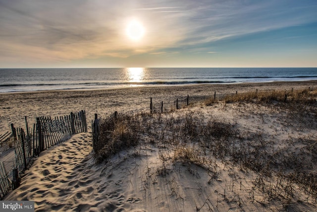 view of water feature featuring a beach view and fence