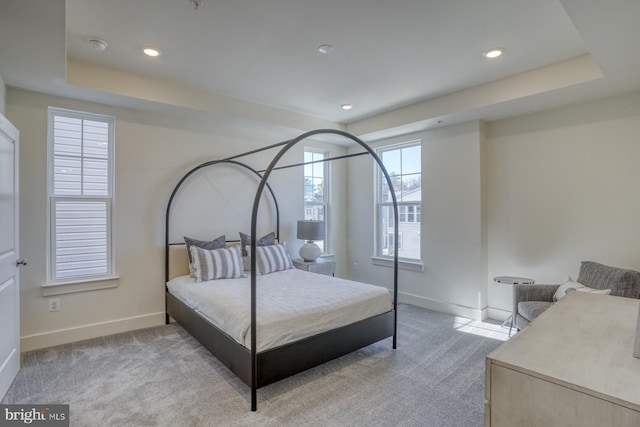 bedroom featuring baseboards, light carpet, recessed lighting, and a tray ceiling