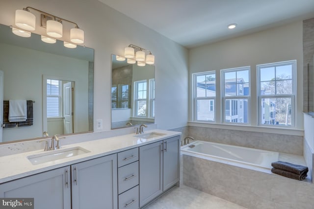 full bath featuring a sink, a bath, double vanity, and tile patterned flooring