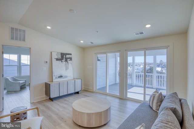 living room featuring visible vents, recessed lighting, vaulted ceiling, and light wood-type flooring