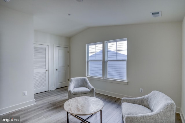 sitting room featuring vaulted ceiling, visible vents, baseboards, and wood finished floors