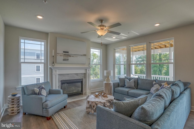 living room with ceiling fan, light wood-type flooring, and a high end fireplace