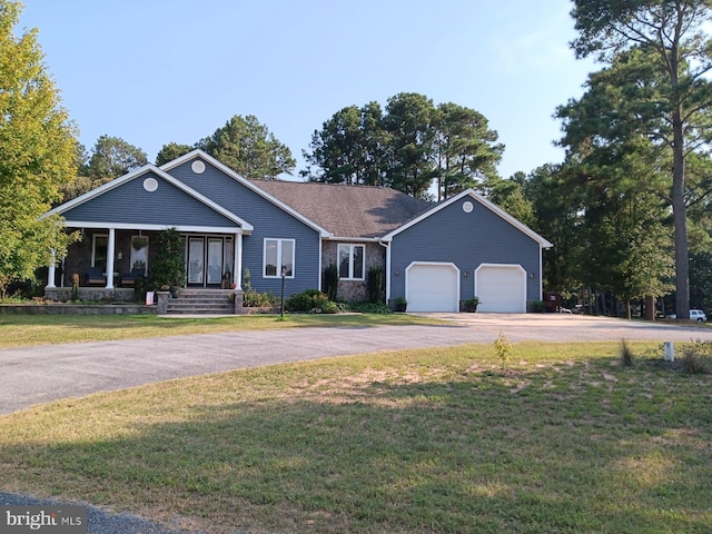 view of front of home featuring a garage, a front yard, and a porch