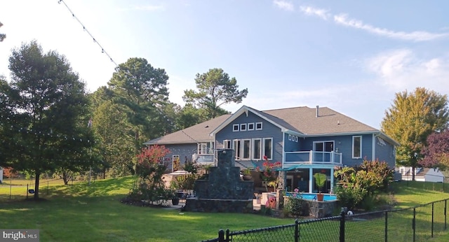 back of house with a lawn, fence private yard, a balcony, and a fenced in pool