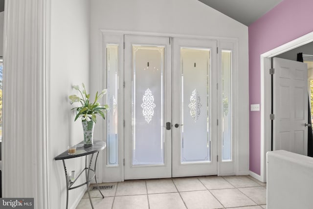 doorway with vaulted ceiling and light tile patterned flooring