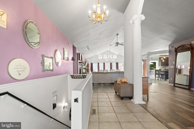 interior space featuring high vaulted ceiling, ceiling fan with notable chandelier, light wood-type flooring, and decorative columns