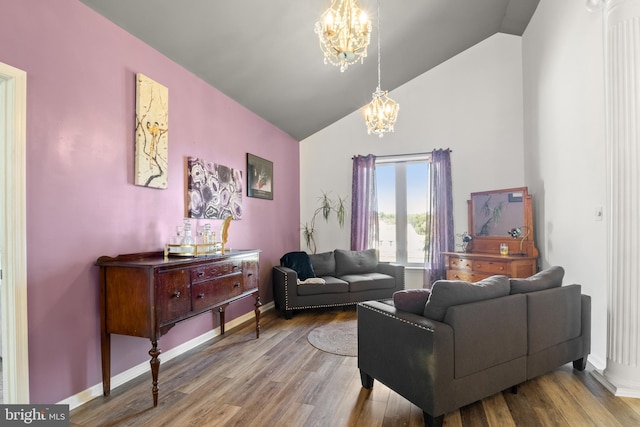 living room with a chandelier, baseboards, wood finished floors, and lofted ceiling