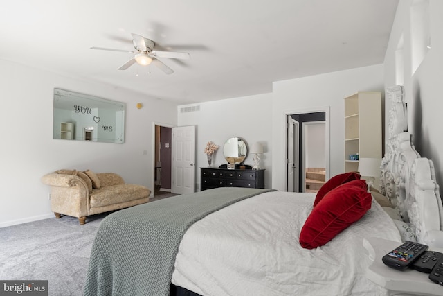 carpeted bedroom featuring ensuite bath, baseboards, visible vents, and ceiling fan