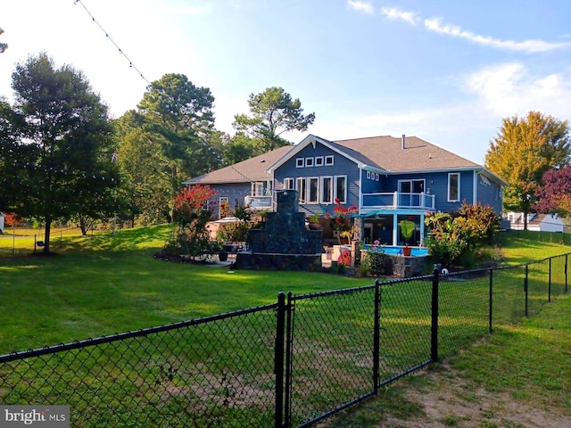 rear view of house with a fenced in pool, a yard, and fence