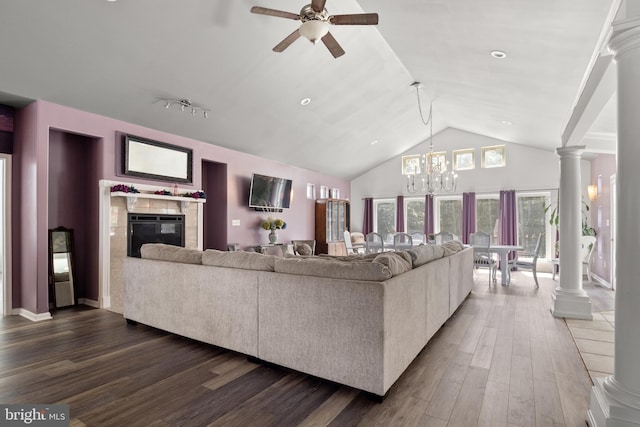 living room featuring a fireplace, ceiling fan with notable chandelier, dark hardwood / wood-style flooring, decorative columns, and high vaulted ceiling