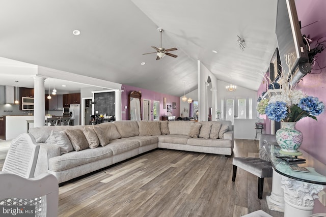 living room featuring vaulted ceiling, ceiling fan with notable chandelier, hardwood / wood-style flooring, and ornate columns