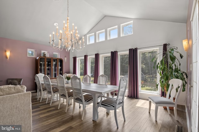 dining space with high vaulted ceiling, wood-type flooring, and a notable chandelier