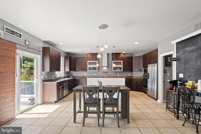 kitchen with wall chimney exhaust hood, pendant lighting, light tile patterned floors, a center island, and stainless steel appliances