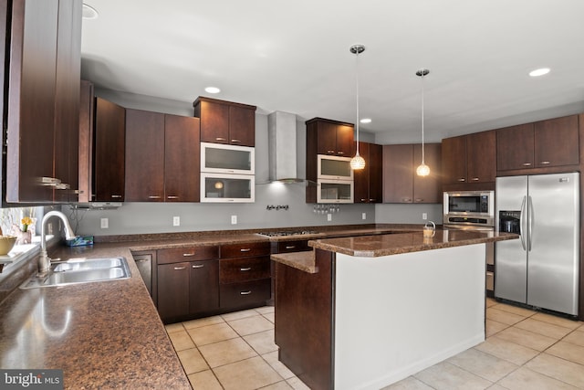 kitchen featuring stainless steel appliances, sink, wall chimney exhaust hood, pendant lighting, and a kitchen island