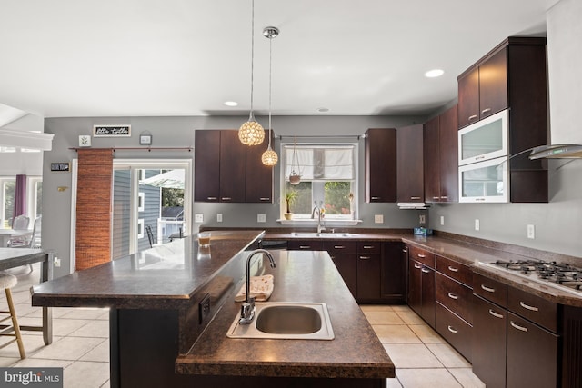 kitchen with a healthy amount of sunlight, dark countertops, a sink, and stainless steel gas stovetop