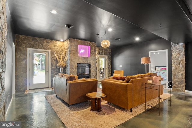 living room with concrete flooring and a stone fireplace