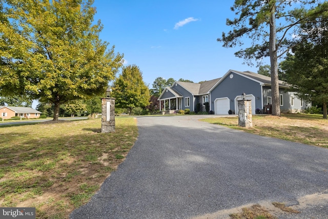 ranch-style home with aphalt driveway, a front yard, and a garage