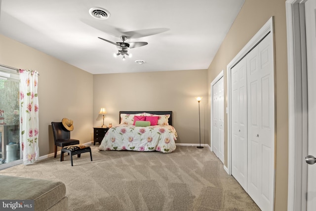 bedroom featuring ceiling fan, light colored carpet, and multiple closets