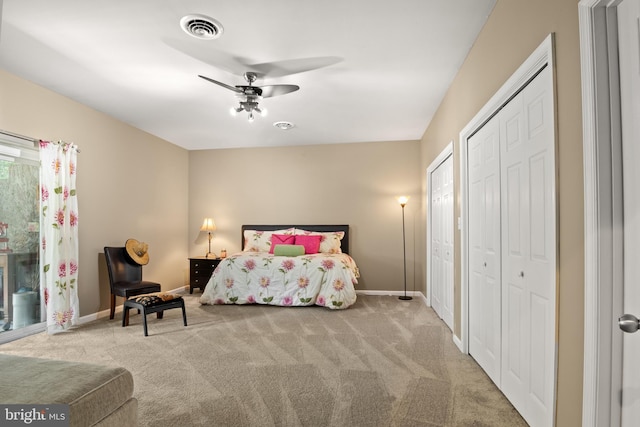 bedroom with baseboards, carpet, visible vents, and multiple closets