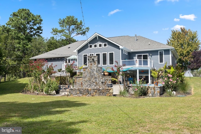 rear view of house featuring a patio area, a lawn, and roof with shingles