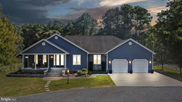 ranch-style home featuring a yard, a porch, and a garage