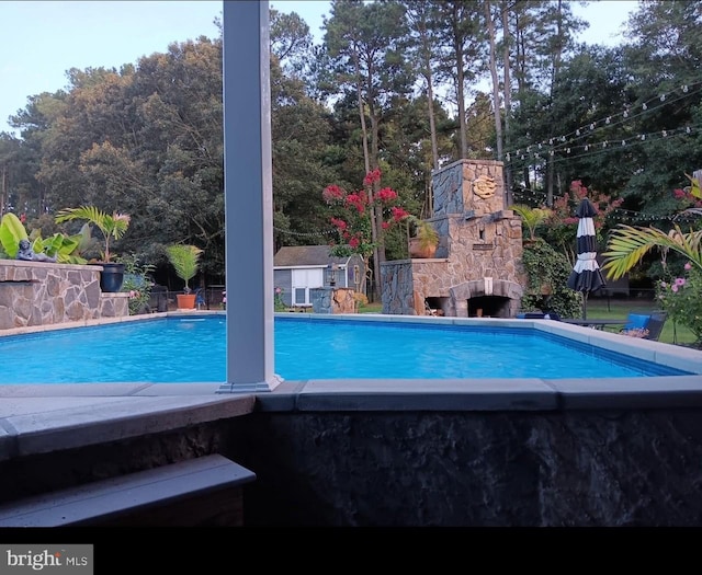 pool featuring fence and an outdoor stone fireplace