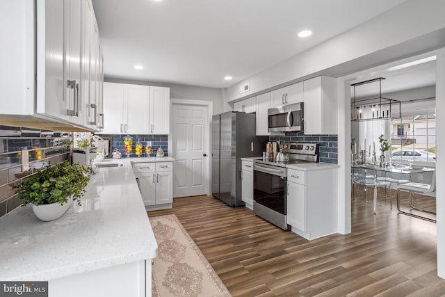 kitchen with dark wood-type flooring, tasteful backsplash, light stone counters, appliances with stainless steel finishes, and white cabinets