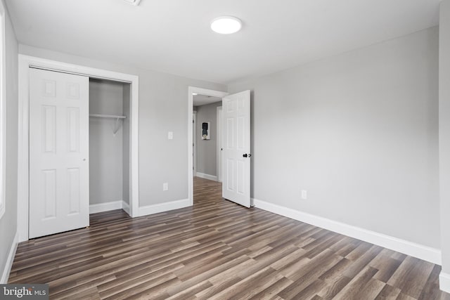 unfurnished bedroom with dark hardwood / wood-style flooring and a closet