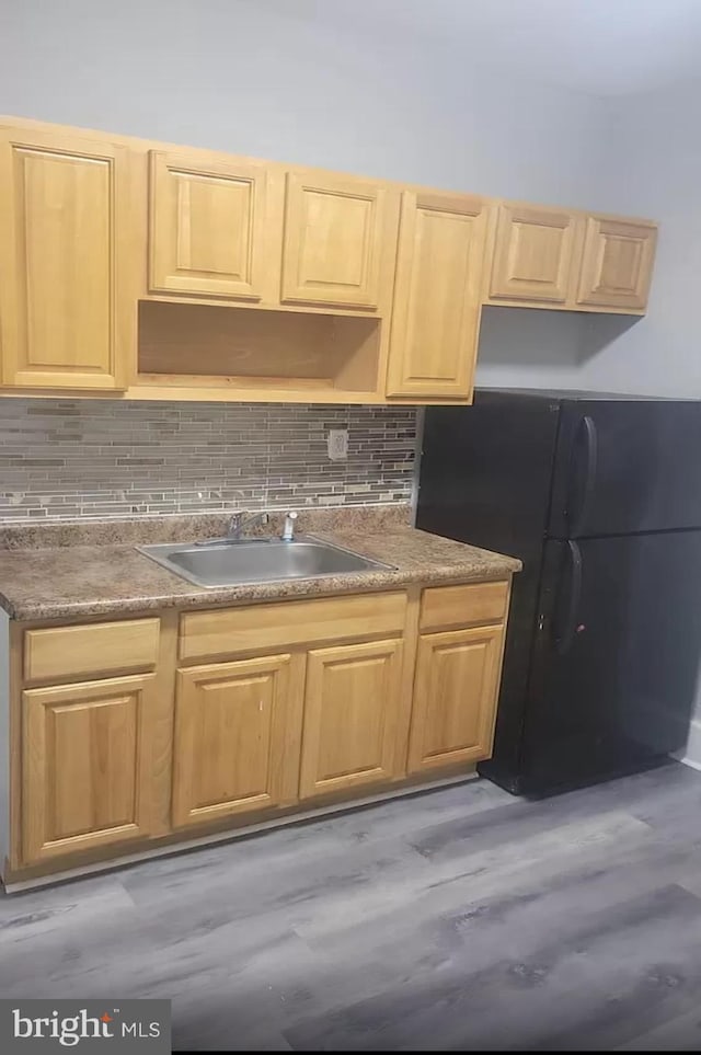 kitchen with a sink, freestanding refrigerator, decorative backsplash, open shelves, and dark countertops