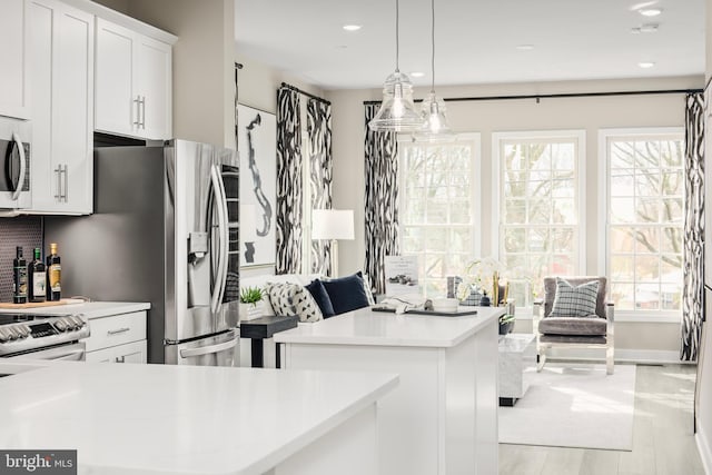 kitchen with electric stove, hanging light fixtures, light hardwood / wood-style floors, white cabinetry, and a center island