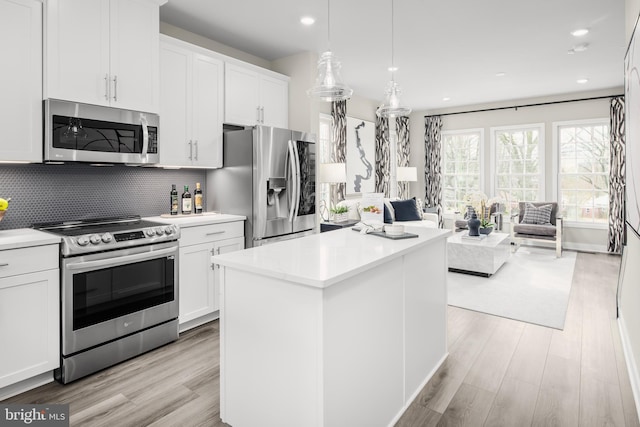 kitchen with stainless steel appliances, white cabinetry, a kitchen island, and decorative backsplash