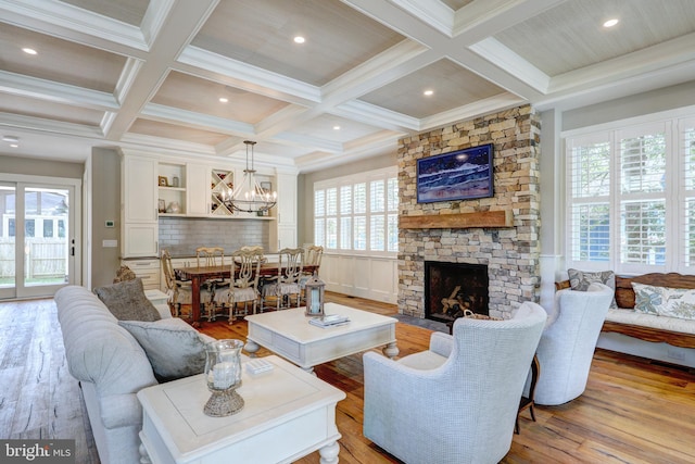 living room with coffered ceiling, a fireplace, light hardwood / wood-style flooring, and a wealth of natural light