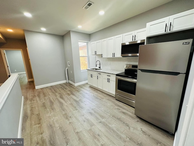 kitchen featuring white cabinets, light hardwood / wood-style floors, and appliances with stainless steel finishes