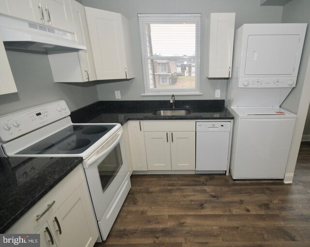 kitchen featuring stacked washer and dryer, white appliances, white cabinets, dark wood-type flooring, and sink