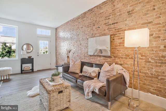 living room with light hardwood / wood-style flooring and brick wall