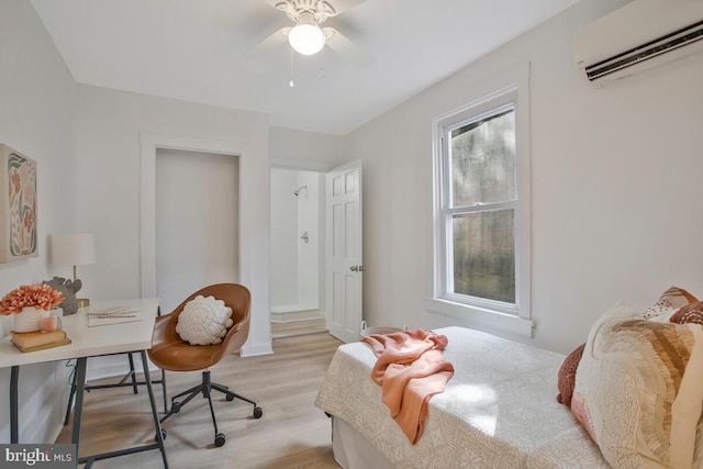 bedroom with light hardwood / wood-style floors, ceiling fan, and a wall mounted air conditioner