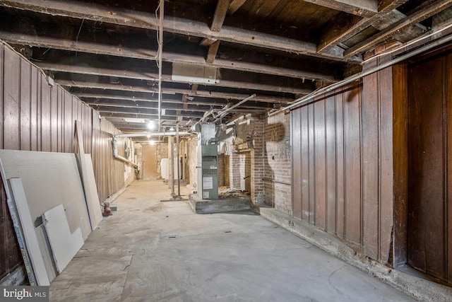 basement with heating unit and wooden walls