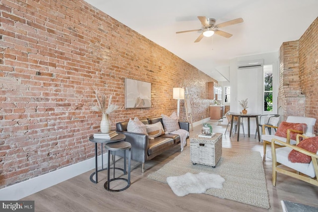 living room featuring brick wall, hardwood / wood-style flooring, an AC wall unit, and ceiling fan