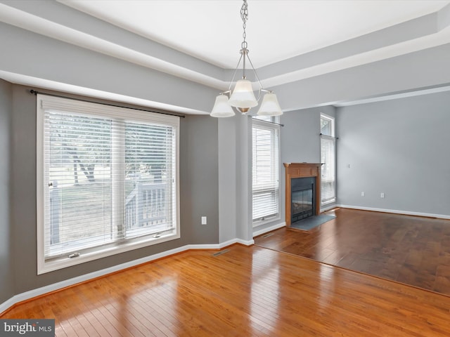 unfurnished living room with hardwood / wood-style floors, plenty of natural light, and an inviting chandelier