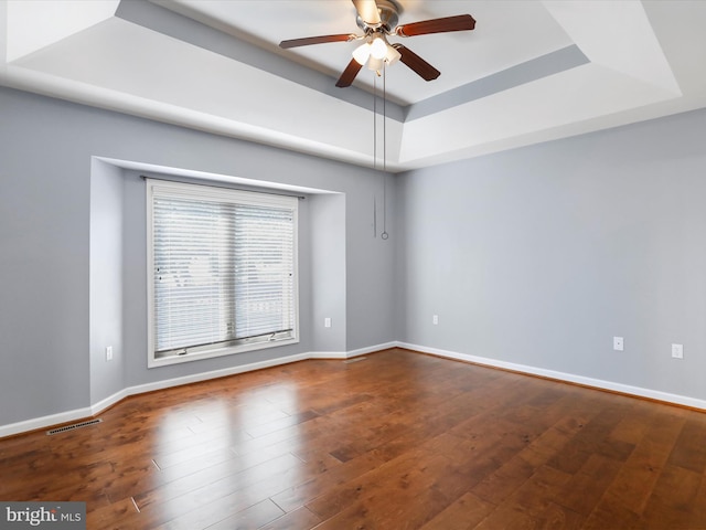 unfurnished room with hardwood / wood-style flooring, ceiling fan, and a tray ceiling