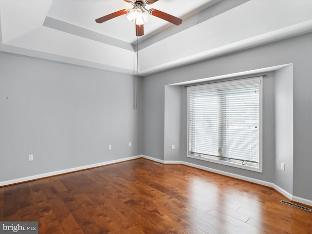 unfurnished room featuring a tray ceiling, hardwood / wood-style floors, and ceiling fan